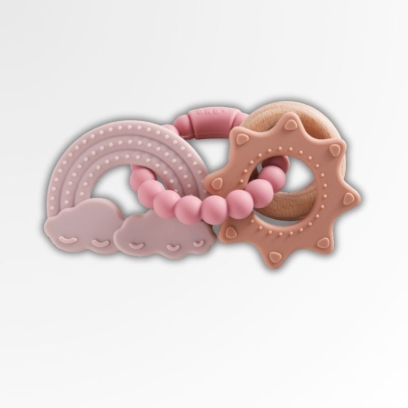 Anneau de dentition Petit Éveil Montessori en silicone rose avec un arc-en-ciel, des nuages et un soleil en bois.