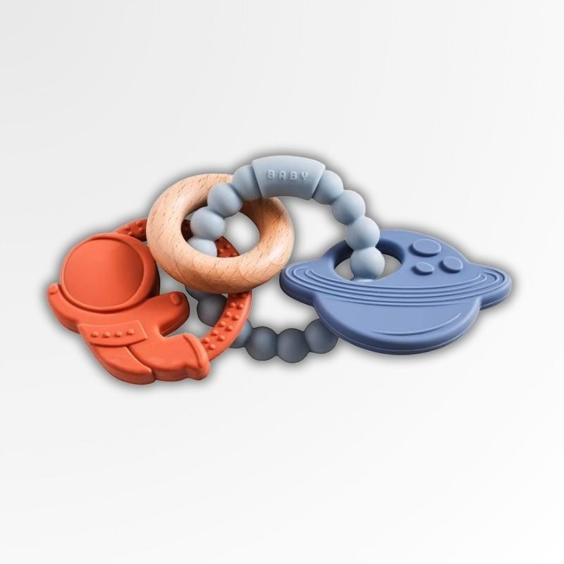Anneau de dentition Petit Éveil Montessori en silicone bleu et orange avec un astronaute, une soucoupe volante et un anneau en bois.