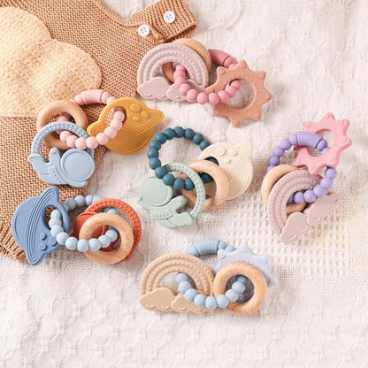 Anneau de dentition Montessori en silicone et bois, formes d'astronaute, planète, arc-en-ciel, soleil, nuages, couleurs pastel.