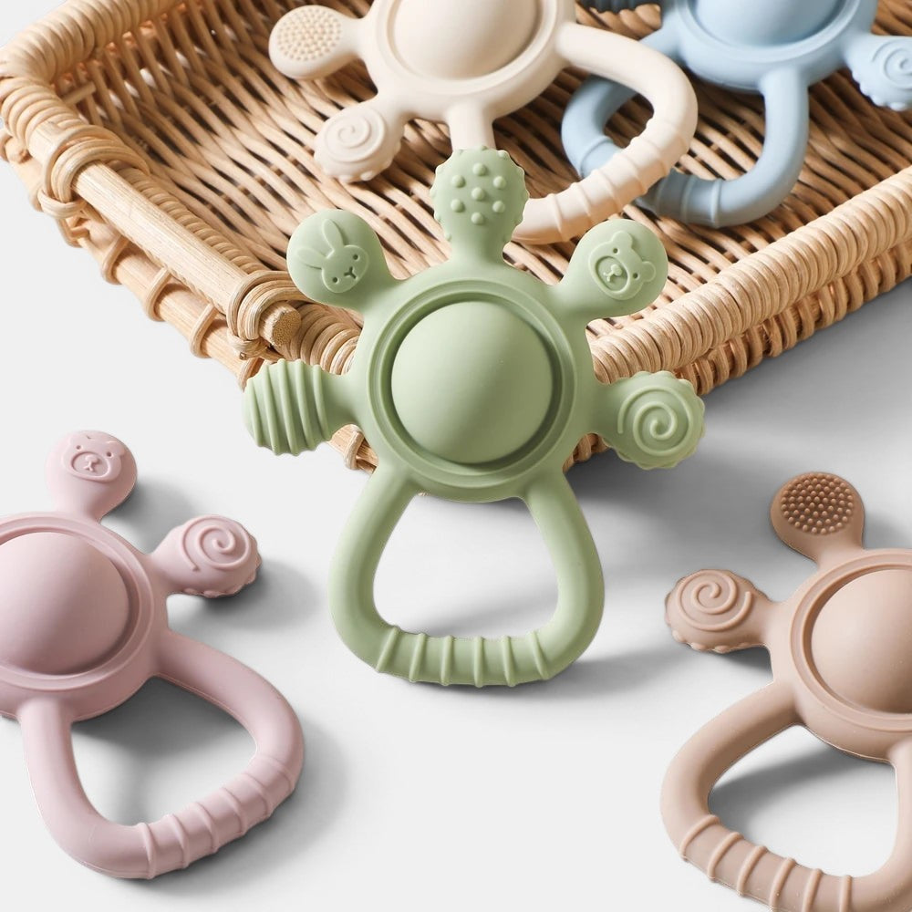 Petit Éveil Montessori : anneau de dentition en silicone vert, rose, beige et bleu, sans BPA, avec formes d'animaux et textures.