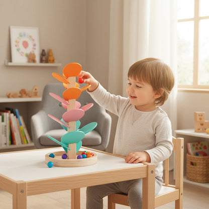 Enfant jouant avec un arbre sonore en bois Mamabrum Petit Éveil Montessori aux feuilles pastel et balles colorées