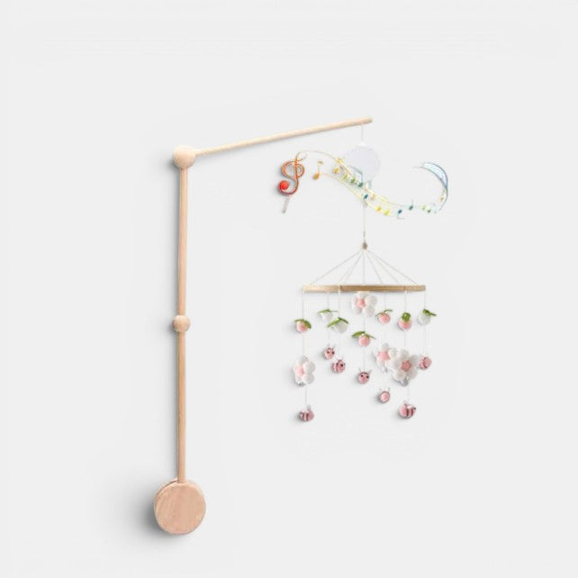 Petit Éveil Montessori arche en bois avec mobile musical, jouets suspendus fleurs et abeilles roses et blanches.
