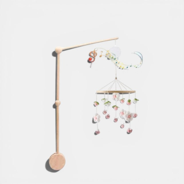 Petit Éveil Montessori arche en bois avec mobile musical, jouets suspendus fleurs et abeilles roses et blanches.