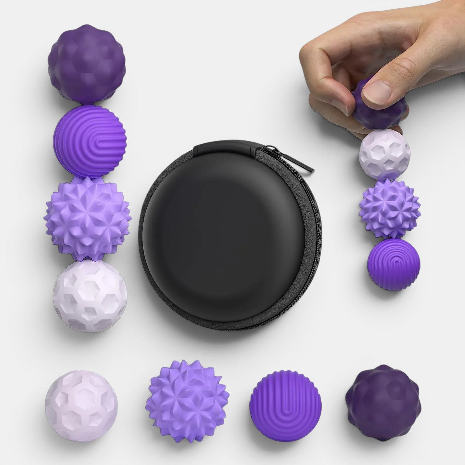 Lot de balles sensorielles magnétiques Montessori violettes et blanches avec différentes textures, livrées dans un étui noir.