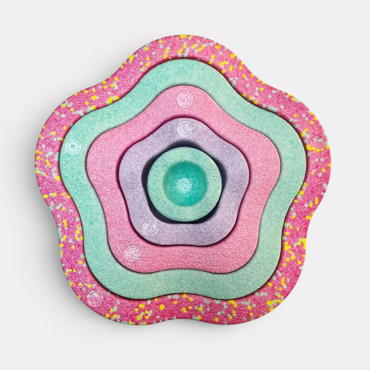 Jouets Stapstones d’équilibre Petit Éveil Montessori, 5 pièces en forme de fleur aux couleurs pastel : rose, violet, menthe, avec un motif de confettis sur le bord.
