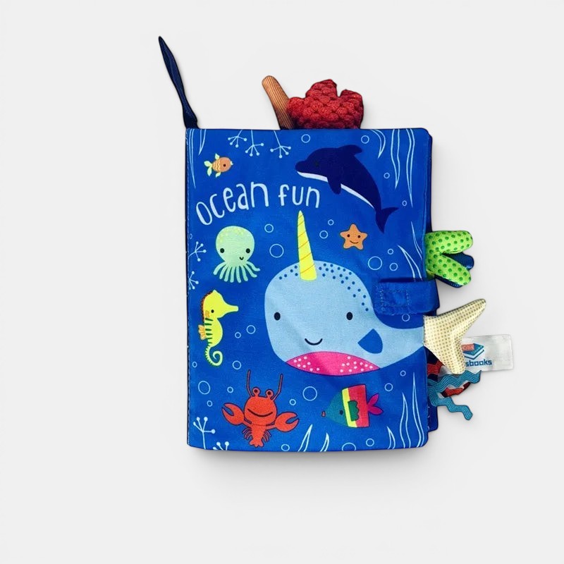 Livre d'éveil en tissu bleu Petit Éveil Montessori avec un narval, un dauphin, un hippocampe et un crabe. Thème océanique.