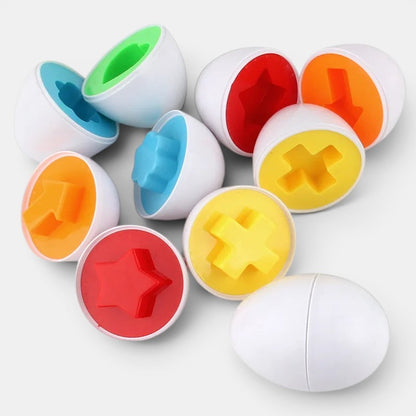 Petit Éveil Montessori : œufs sensoriels en plastique blanc avec formes colorées (rouge, jaune, orange, bleu, vert) pour tri et apprentissage.