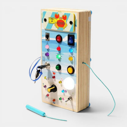 Planche occupée en bois Petit Éveil Montessori avec interrupteurs, lumières LED, clé et boutons pour l'apprentissage de la motricité fine.