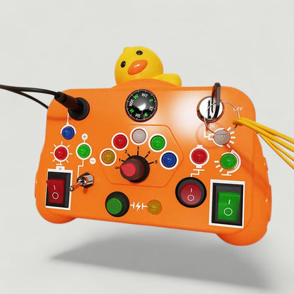 Tableau d'activités Petit Éveil Montessori orange avec un canard jaune, boutons, interrupteurs et boussole.