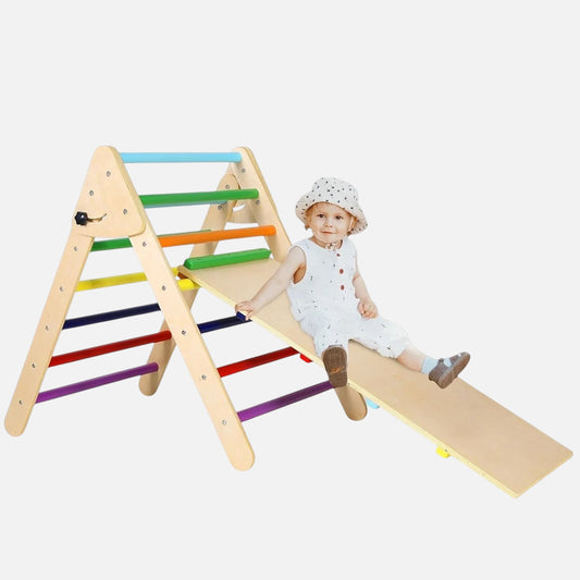 Enfant assis sur la rampe d'un triangle Pikler 2-en-1 en bois Petit Éveil Montessori avec barreaux multicolores